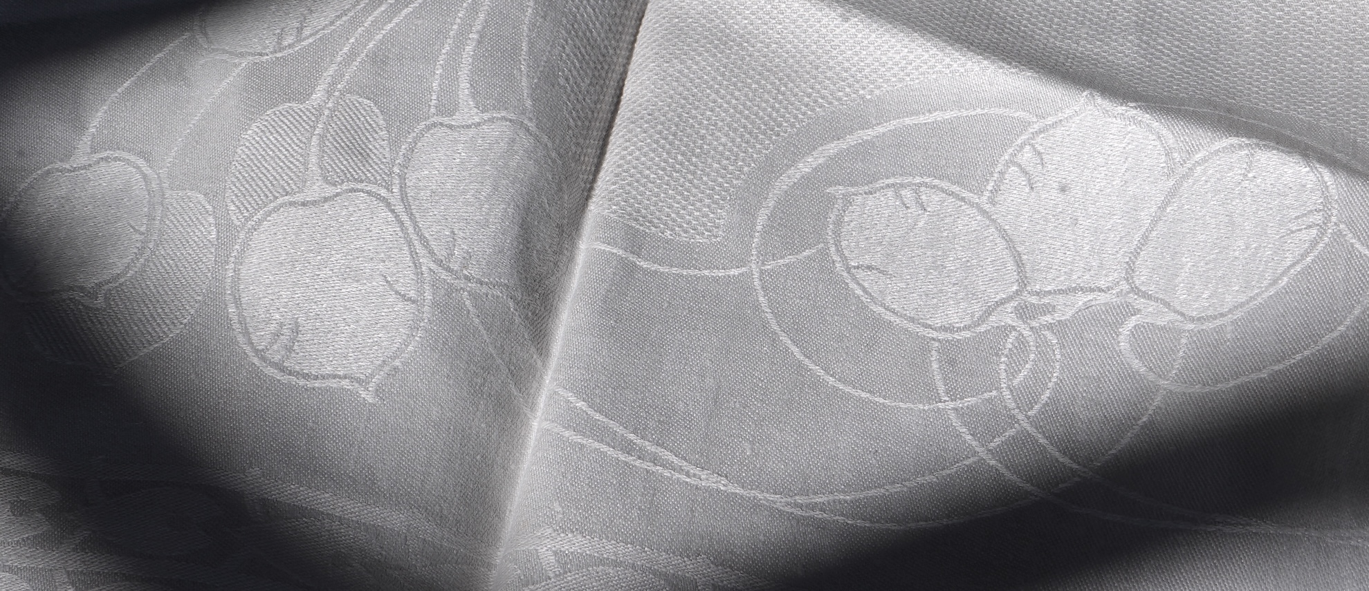 A set of four large Art Nouveau, unused white damask woven hand towels. The pattern having strong Archibald Knox and Walter Crane design elements; with trailing Honesty seeds and Tulip flower heads, these motifs much use